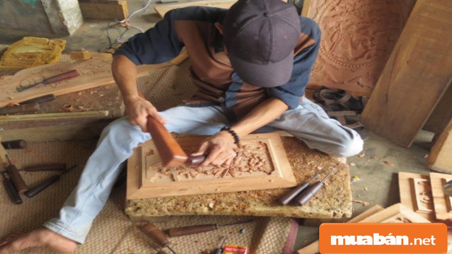Thợ mộc đang chạm trổ, khắc họa tiết vào một sản phẩm gỗ.